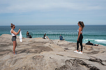 Sydney  Australien  Junge Frau fotografiert auf den Klippen am Tamarama Point ihre Freundin