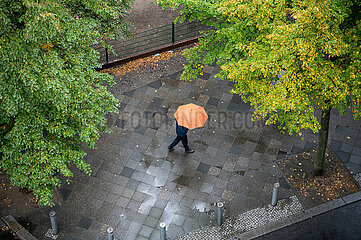 Berlin  Deutschland  Person mit Regenschirm geht an einem regnerischen Herbsttag die Strasse entlang