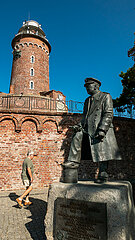 Polen  Kolobrzeg - Der Leuchtturm Kolobrzeg ist das Wahrzeichen der Stadt an der Ostseekueste mit Denkmal des Offiziers Stanislaw Mieszkowski geboren 1903  1952 von Stalinisten hingerichtet