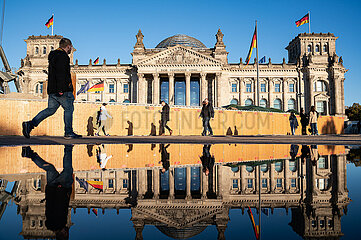 Berlin  Deutschland  Menschen gehen am Reichstag vorbei  der sich in einer grossen Pfuetze spiegelt