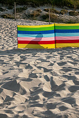 Polen  Dzwirzyno - Sillhouette eines Urlaubers hinter einem Windschutz am Strand