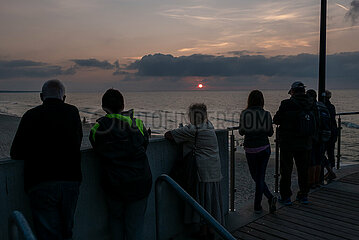 Polen  Kolobrzeg - Urlauber geniessen den Sonnenuntergang am Ostseestrand