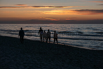 Polen  Kolobrzeg - Sillhouetten von Urlaubern bei Sonnenuntergang an der Ostseekueste