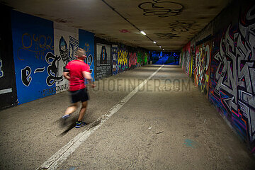 Polen  Poznan - Jogger in gut ausgeleuchtetem Fussgaengertunnel am Abend
