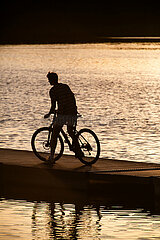 Polen  Poznan - Silhouette eines Teenagers mit Fahrrad an einem Badesee im Stadtgebiet
