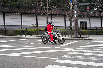 Kyoto  Japan  Motorradfahrer im Weihnachtsmannkostuem wartet an einer Fussgaengerampel