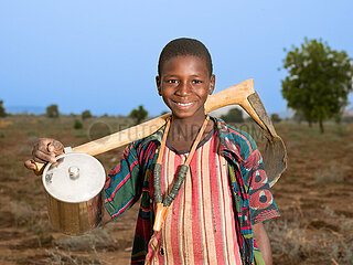Traditionelles Dorf in der Sahelzone - Junge mit Feldhacke