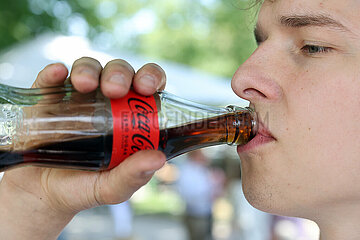 Hannover  Deutschland  junger Mann trinkt Coca Cola aus einer Flasche