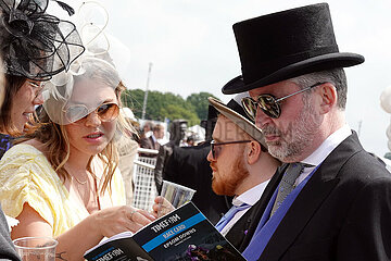 Epsom Downs  Fashion: Audience look into the racecard at the racecourse