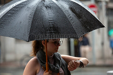 Republik Irland  Dublin - Junge Frau mit Regenschirm schaut auf die Uhr  regnerischer Tag in der Stadt (Stadtzentrum)