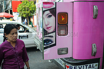 Yangon  Myanmar  Strassenszene mit Werbung an einem Bus und einer vorbeigehenden Frau