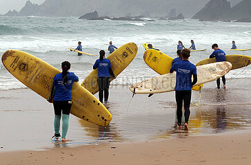 Sagres  Portugal  Menschen tragen bei einem Surfkurs ihre Surfbretter ins Wasser