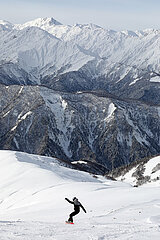 Mestia  Georgien  Snowboardfahrer faehrt im Skigebiet Tednuldi einen Hang hinunter