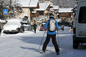 Mestia  Georgien  Skifahrer faehrt auf einer verschneiten Strasse durch die Stadt