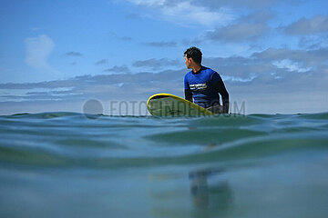 Raposeira  Portugal  Teenager sitzt im Meer auf seinem Surfbrett