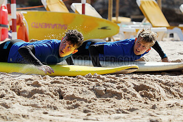 Raposeira  Portugal  Teenager liegen bei einem Surfkurs am Strand auf ihren Surfbrettern