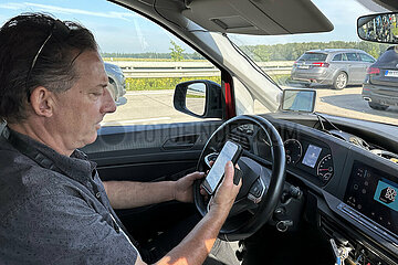Westenholz  Deutschland  Autofahrer schaut im Stau auf der A7 auf sein Smartphone