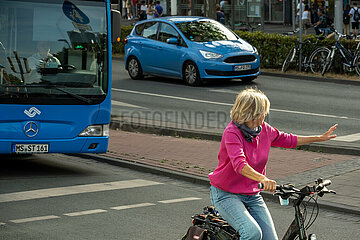 Deutschland  Muenster - Seniorin auf dem Fahrrad auf einer Hauptstrasse in der City