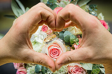 Herz-Hände vor einem Brautstrauß