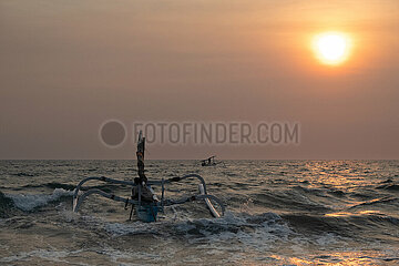 Senggigi  Indonesien  Maenner fahren mit ihren Jukungs bei Sonnenuntergang ueber das Meer. Ein Jukung ist ein traditionelles indonesisches Fischerboot