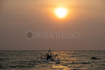 Senggigi  Indonesien  Mann faehrt mit seinem Jukung bei Sonnenuntergang ueber das Meer. Ein Jukung ist ein traditionelles indonesisches Fischerboot