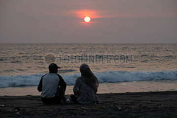 Senggigi  Indonesien  Mann und Frau sitzen bei Sonnenuntergang am Strand