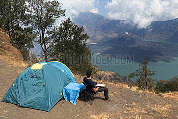 Senaru  Indonesien  Mann sitzt neben seinem Zelt im Camp am Senaru-Kraterrand auf dem Mount Rinjani