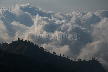Senaru  Indonesien  Wolken tuermen sich ueber den Huegeln auf dem Mount Rinjani