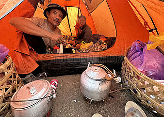 Senaru  Indonesien  Maenner sitzen in einem Zelt