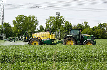 Berlin  Deutschland - Ein Traktor mit einer Anhaengespritze bringt ein Pflanzenschutzmittel auf einem Getreidefeld aus.