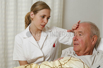 junge Krankenpflegerin am Bett eines aelteren Mannes | Hauspflege   Krankenpflegerin am Bett eines aelteren Mannes