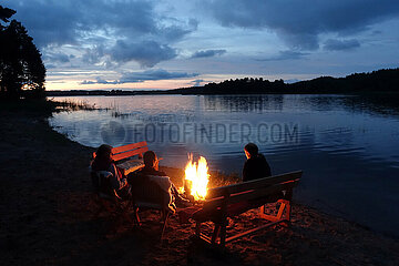 Lanken  Polen  Menschen sitzen am Ufer des Jezioro Gwiazdy an einem Lagerfeuer