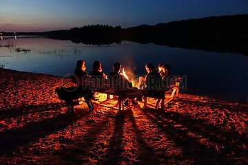 Lanken  Polen  Menschen sitzen am Ufer des Jezioro Gwiazdy an einem Lagerfeuer