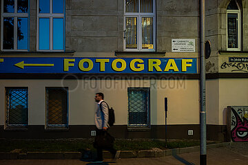 Polen  Poznan - Mann geht vorbei  dahinter ein Hinweisschild fuer einen Fotografen