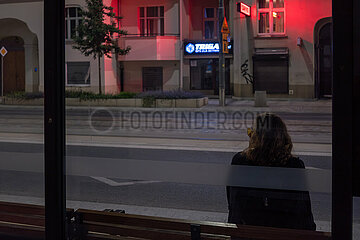 Polen  Poznan - junger Mann mit langen Haaren wartet an einer Strassenbahnhaltestelle