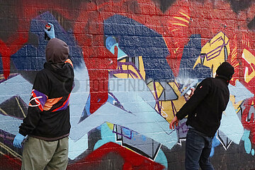 Berlin  Deutschland  Jugendliche spruehen Graffiti an eine Wand