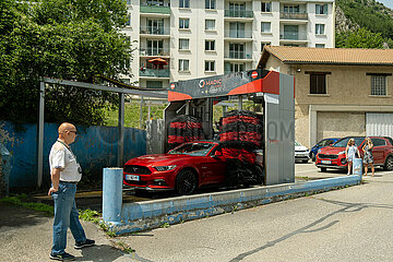 Frankreich  Veynes - Besitzer eines Roten Sportwagens  Autowaesche in dem Ort in den Alpen
