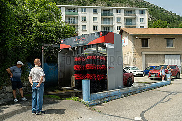 Frankreich  Veynes - Besitzer eines Roten Sportwagens  Autowaesche in dem Ort in den Alpen