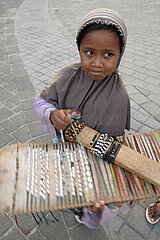 Kuta  Indonesien  Kind verkauft auf einem Wochenmarkt Armbaender