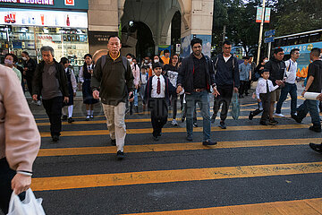 Hong Kong  China  Menschen ueberqueren auf einem Zebrastreifen eine Strasse