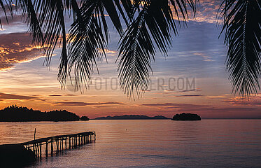 Togianinseln  Sulawesi  Indonesien  Malerischer Sonnenuntergang ueber einem paradiesischen Palmenstrand einer tropischen Insel