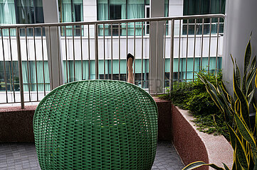 Singapur  Republik Singapur  Frau sitzt in einem Korbsessel auf der Green Oasis Gartenterrasse