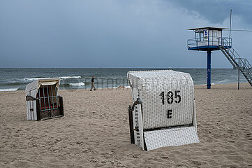 Heringsdorf  Usedom  Dunkle Wolken am leeren Sandstrand mit Turm der Badeaufsicht und traditionellen Strandkoerben