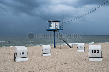 Heringsdorf  Usedom  Dunkle Wolken am leeren Sandstrand mit Turm der Badeaufsicht und traditionellen Strandkoerben