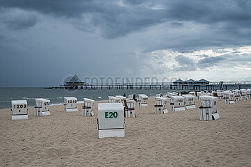 Heringsdorf  Usedom  Dunkle Wolken ziehen ueber den leeren Sandstrand mit der Seebruecke im Hintergrund