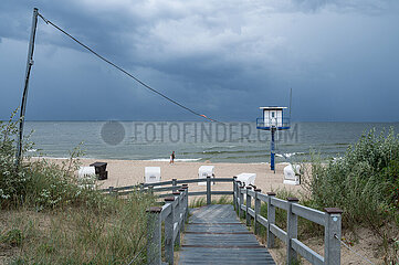 Heringsdorf  Usedom  Dunkle Wolken am leeren Sandstrand mit Turm der Badeaufsicht und traditionellen Strandkoerben