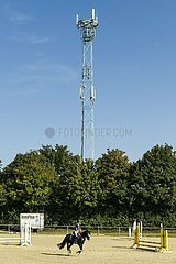 Mobilfunkmast überragt Reitplatz  sorgt für Empfang auf dem Land.