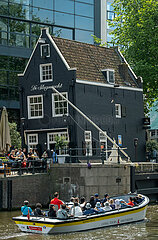 Niederlande  Amsterdam - Ausflugsboot im Grachtenguertel vor De Sluyswacht  Gastronomie in einem historischen und schief stehendem Haus