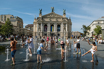 Ukraine  Lwiw - Kinder und Jugendliche erfrischen sich an Wassersauelen vor der Oper am Prospekt Svobody