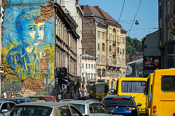 Ukraine  Lwiw - Stau auf einer Hauptstrasse im Stadtzentrum und Wandbild mit einem Maedchen in ukrainischen Farben